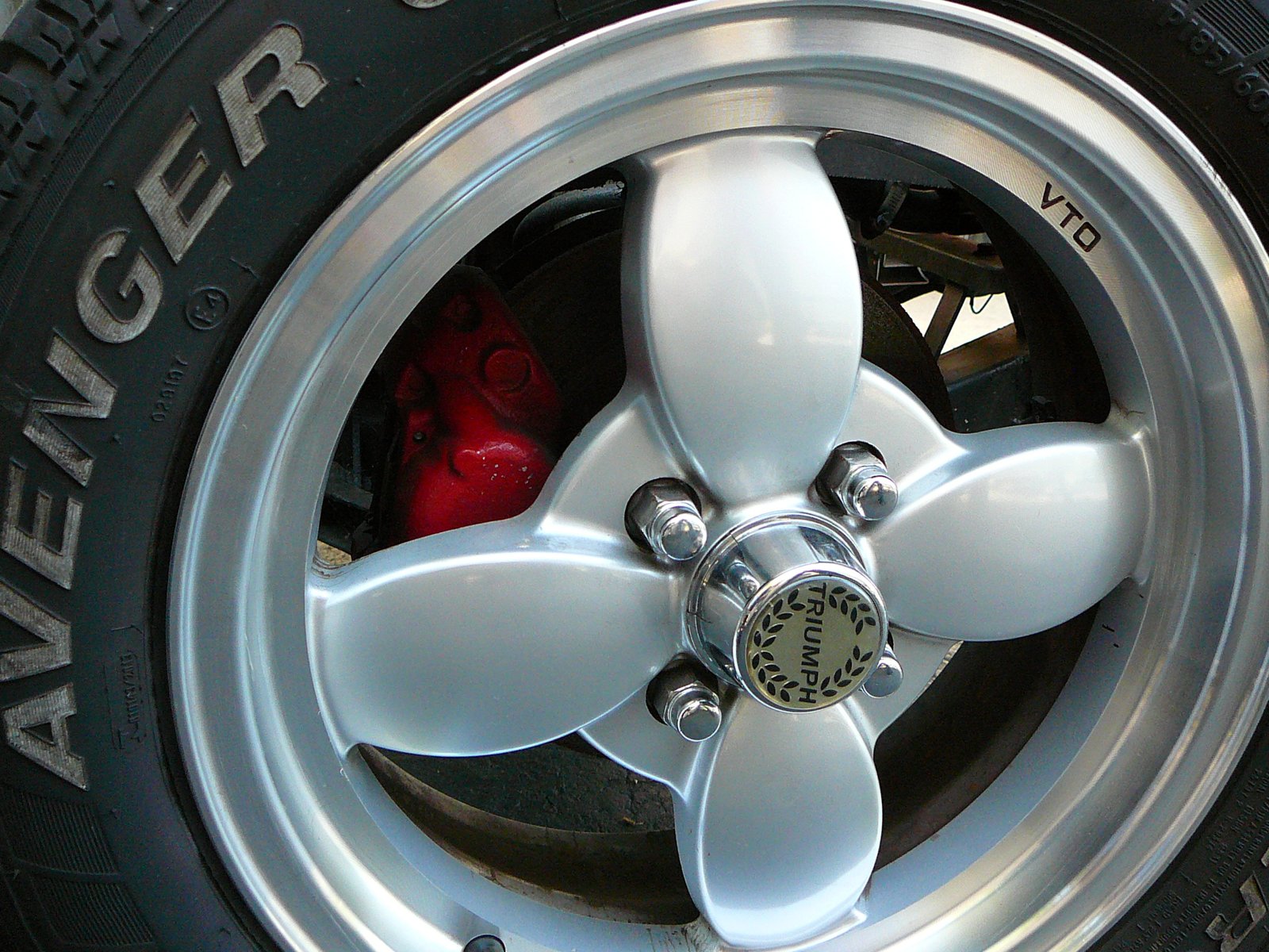 Close up of a VTO wheel on a Triumph Spitfire with a Triumph laurel center cap