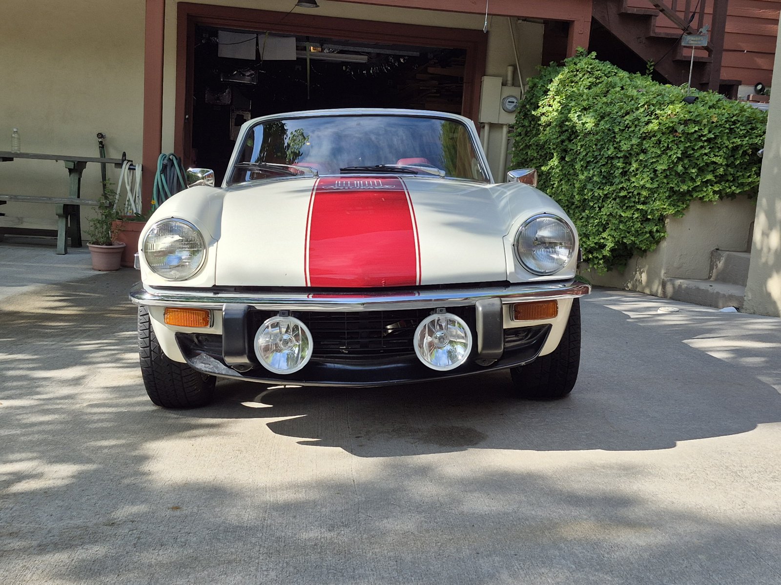 Front view of a white 1972 Triumph Spitfire Mk IV with a red racing stripe